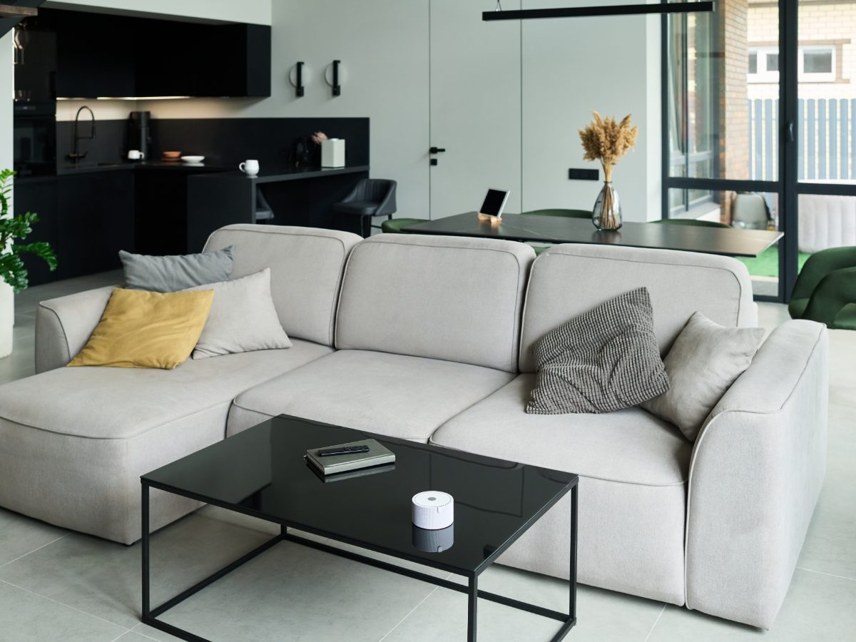 A light grey sectional sofa with a chaise and scatter cushions, in an open-plan living room.